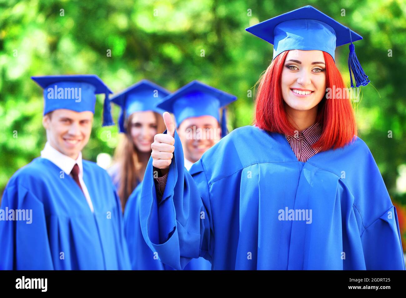 Graduate students wearing graduation hat and gown, outdoors Stock Photo