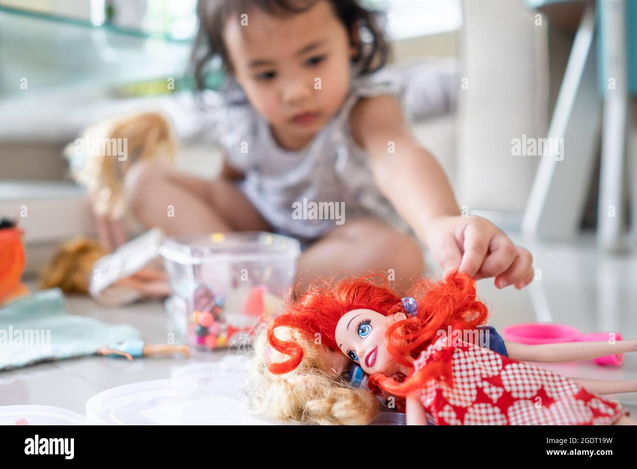A Thai cute little girl playing doll at home Stock Photo - Alamy