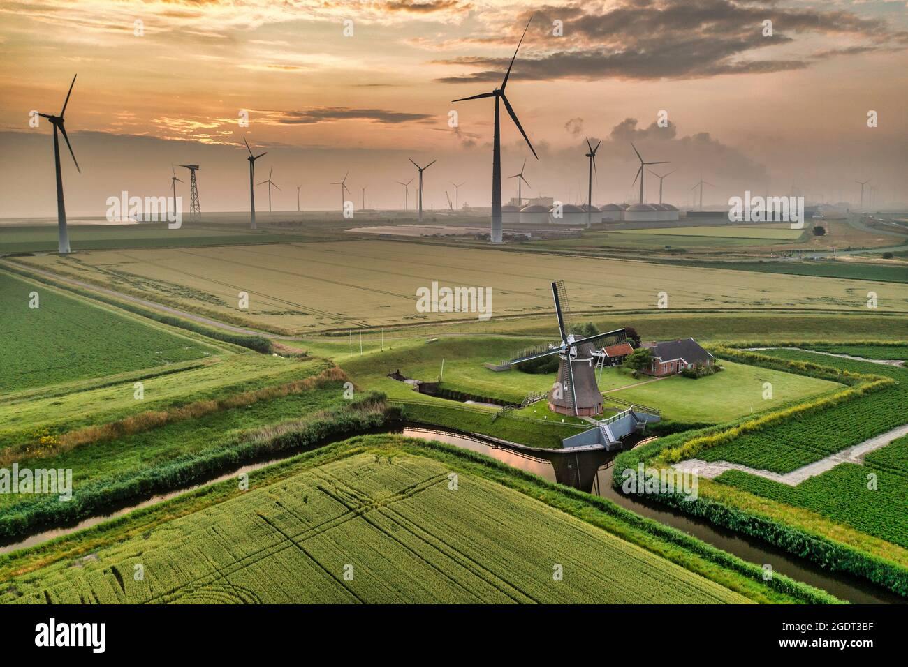 The Netherlands. Eemshaven. Wind park Eemsmond. Wind turbines. Foreground: ancient windmill (1897) called Goliath. Sunrise. Aerial. Stock Photo