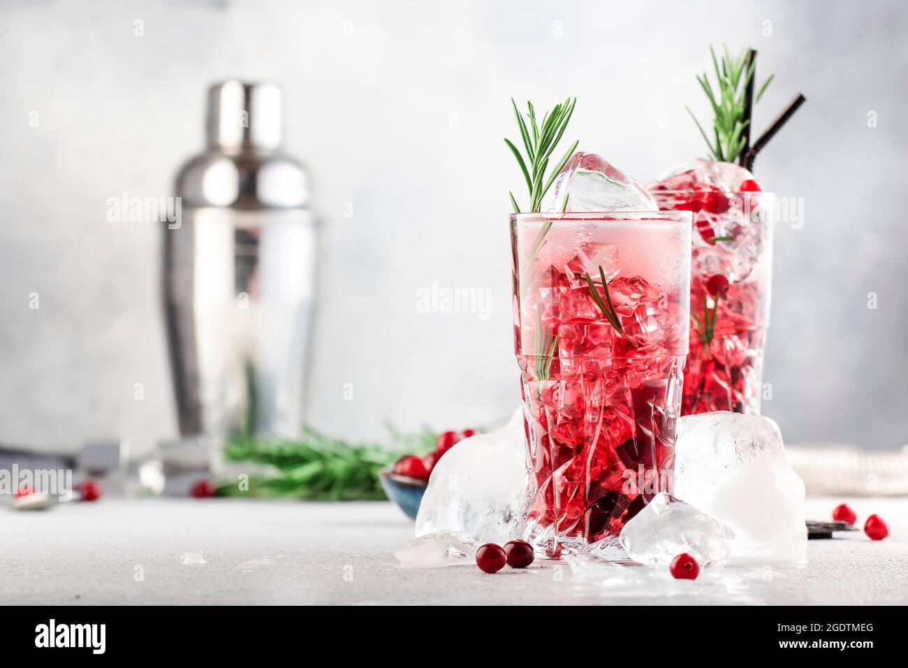 Cranberry cocktail with vodka, ice, juice, rosemary and red berries in