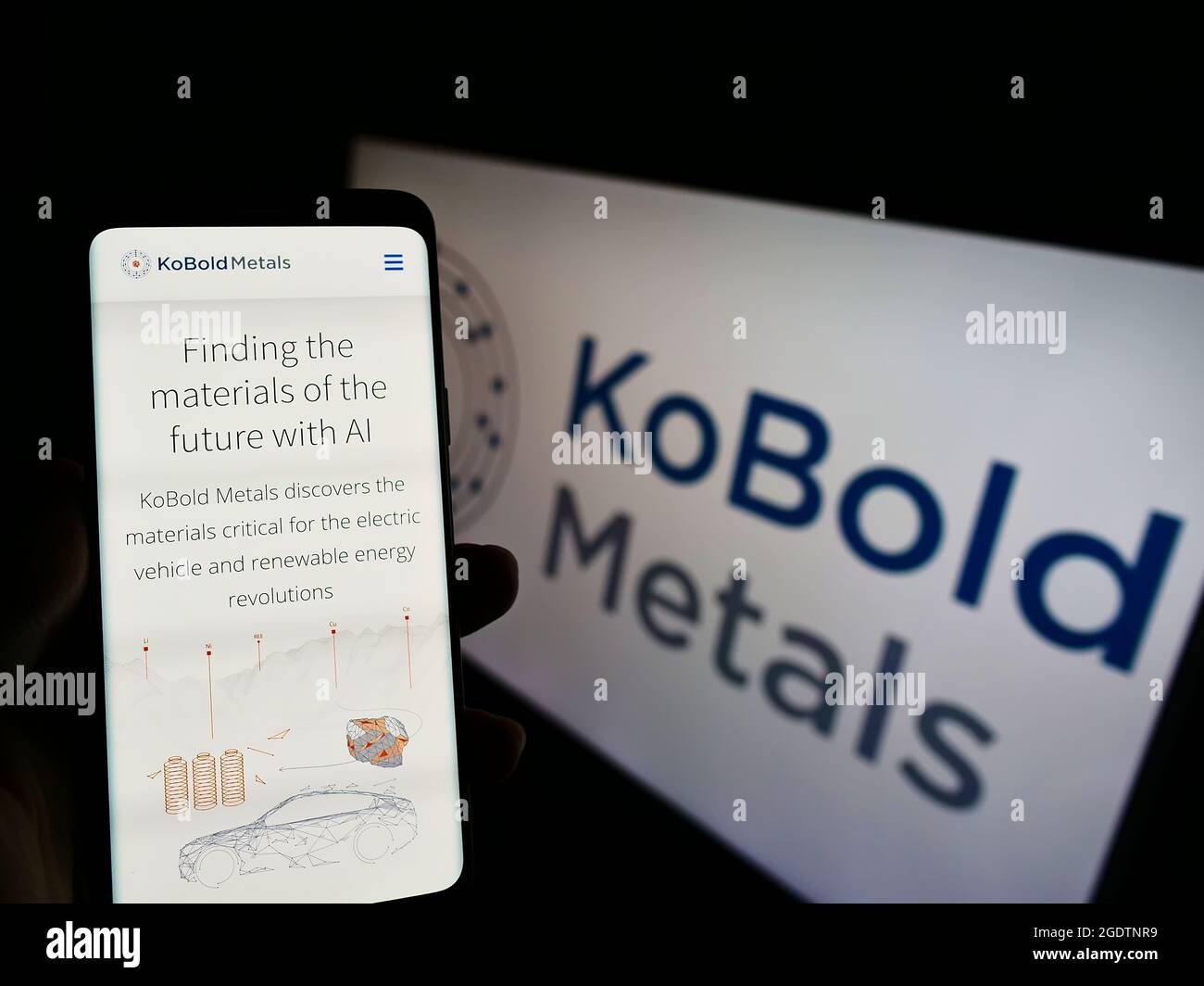 Person holding cellphone with website of US mining technology company KoBold Metals on screen in front of logo. Focus on center of phone display. Stock Photo