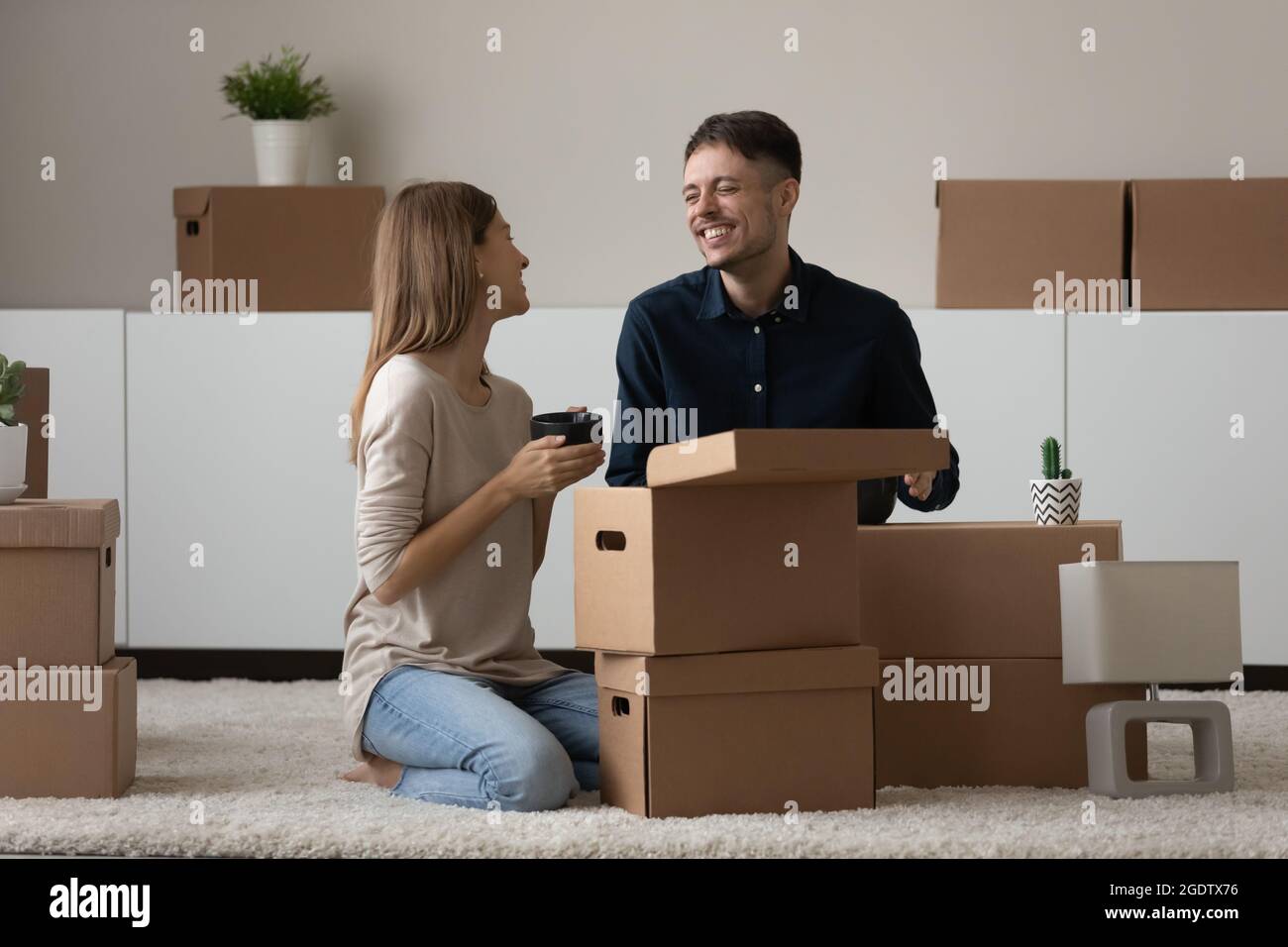 Couple unpack belongings enjoy talk celebrate relocation to own house Stock Photo