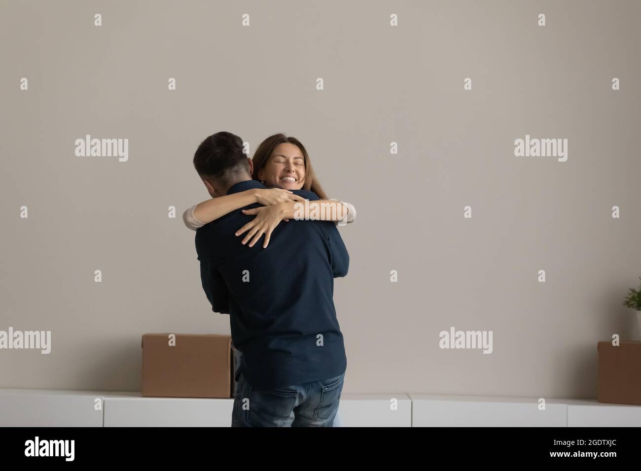 Happy couple standing in unfurnished room cuddling celebrate relocation day Stock Photo