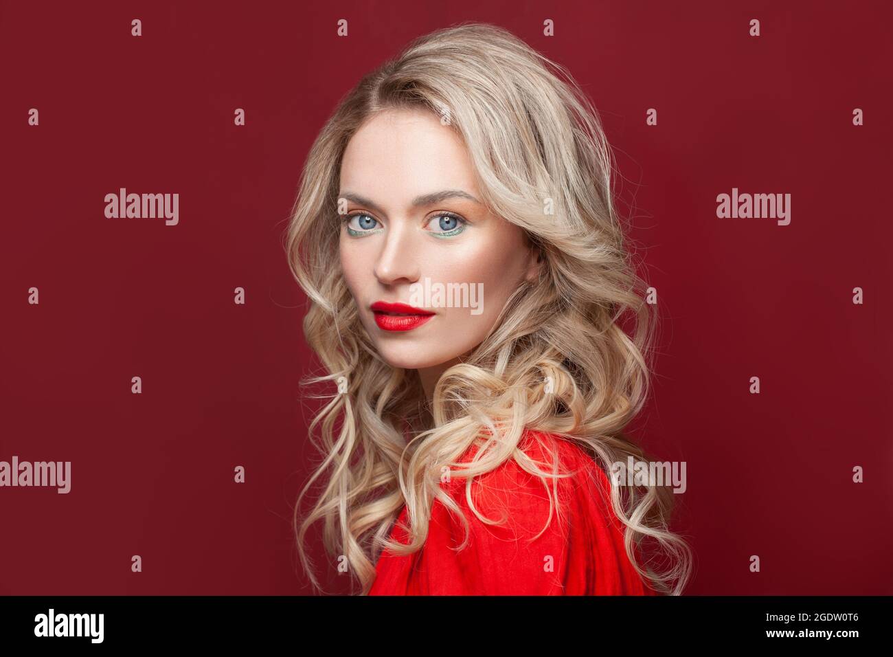 Blonde curly long hair woman with beauty makeup over red background Stock Photo