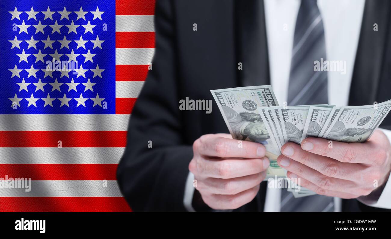Dollars banknotes in male hands on National USA flag background Stock Photo