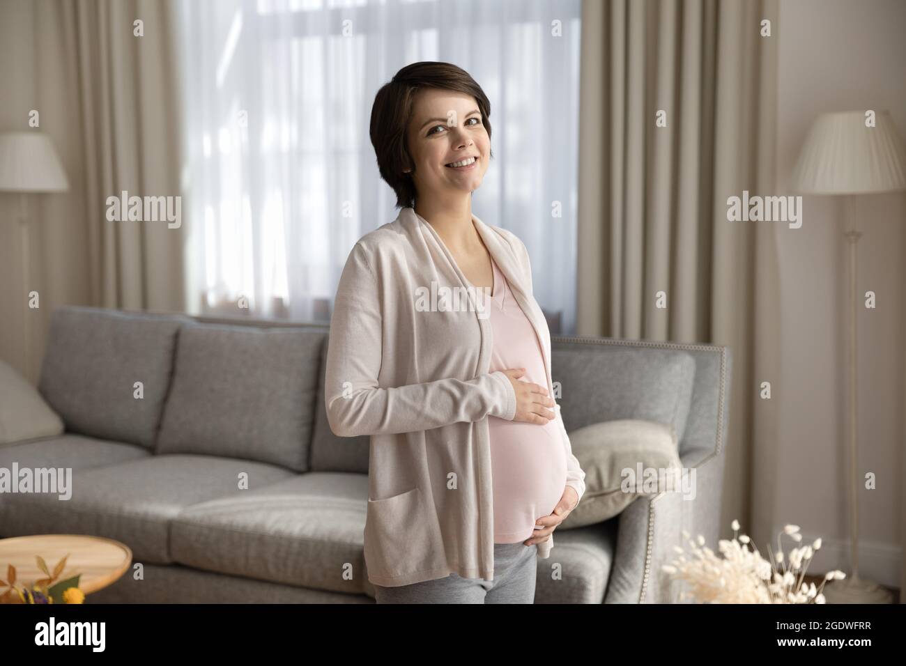 Portrait of happy young pregnant woman holding big tummy Stock Photo