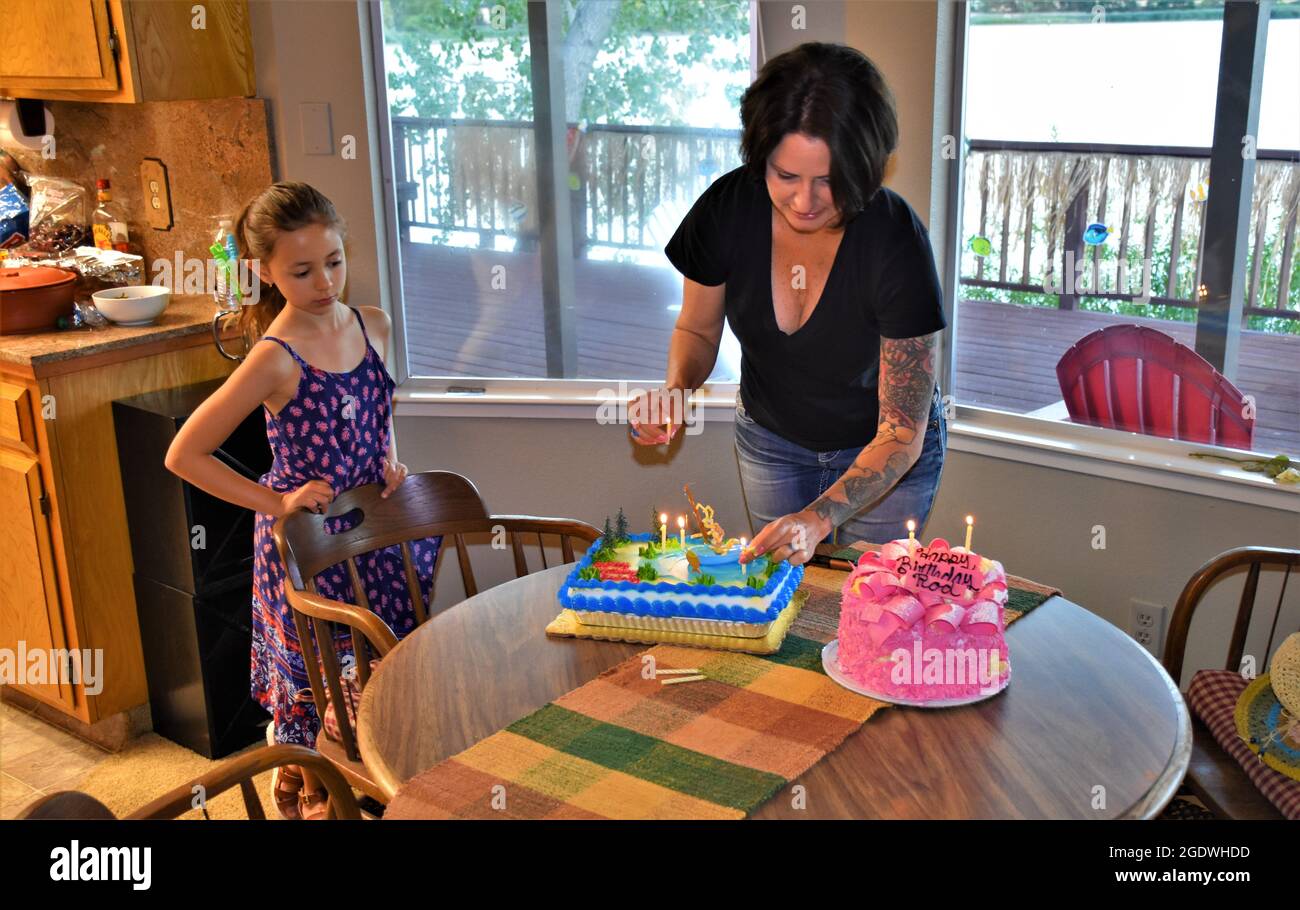 Woman and her daughter putting touches on dad's birthday cake for a surprise party later Stock Photo