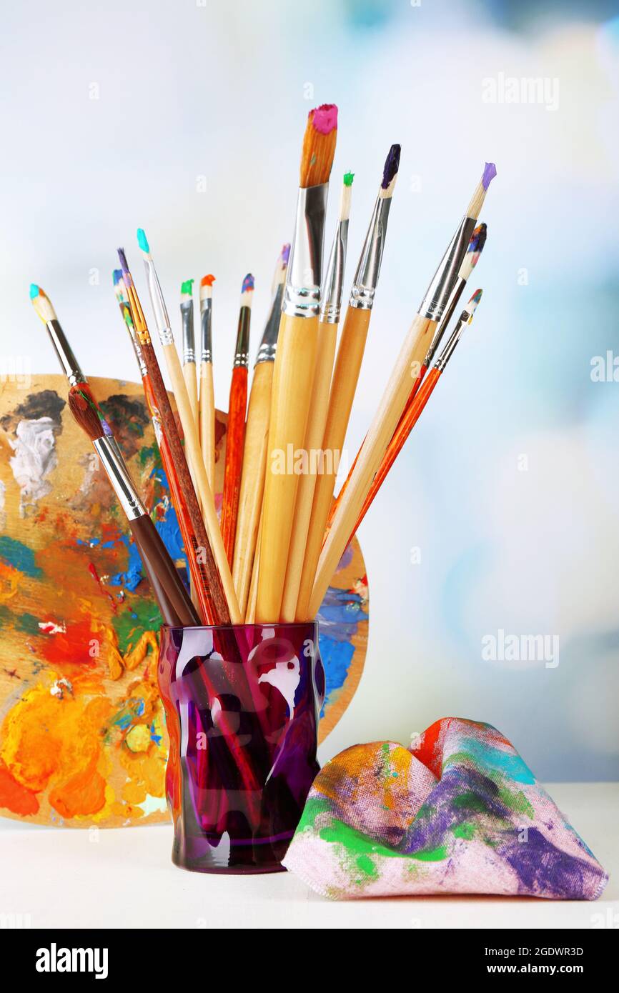 Paint brushes with paints and palette on bright background Stock Photo