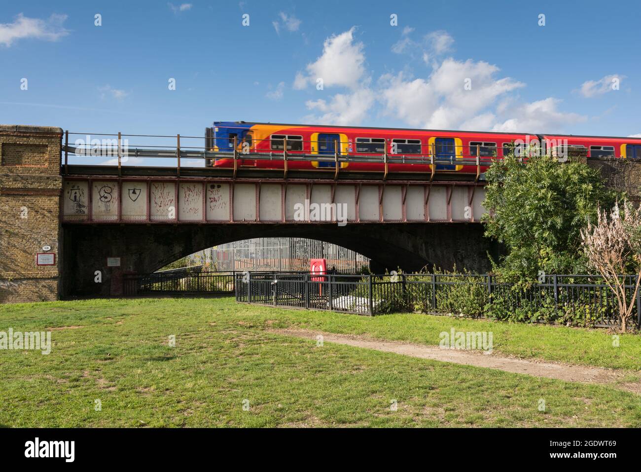 A South Western Railway commuter train passing over the River Wandle, a tributary of the River Thames, in Wandsworth, London, England, UK Stock Photo