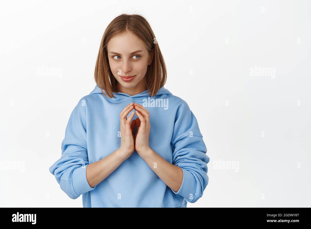 Hmm interesting. Young woman scheming smth, looking aside with smug face, steeple fingers cunning, has devious evil genius plan, stare mysterious at Stock Photo