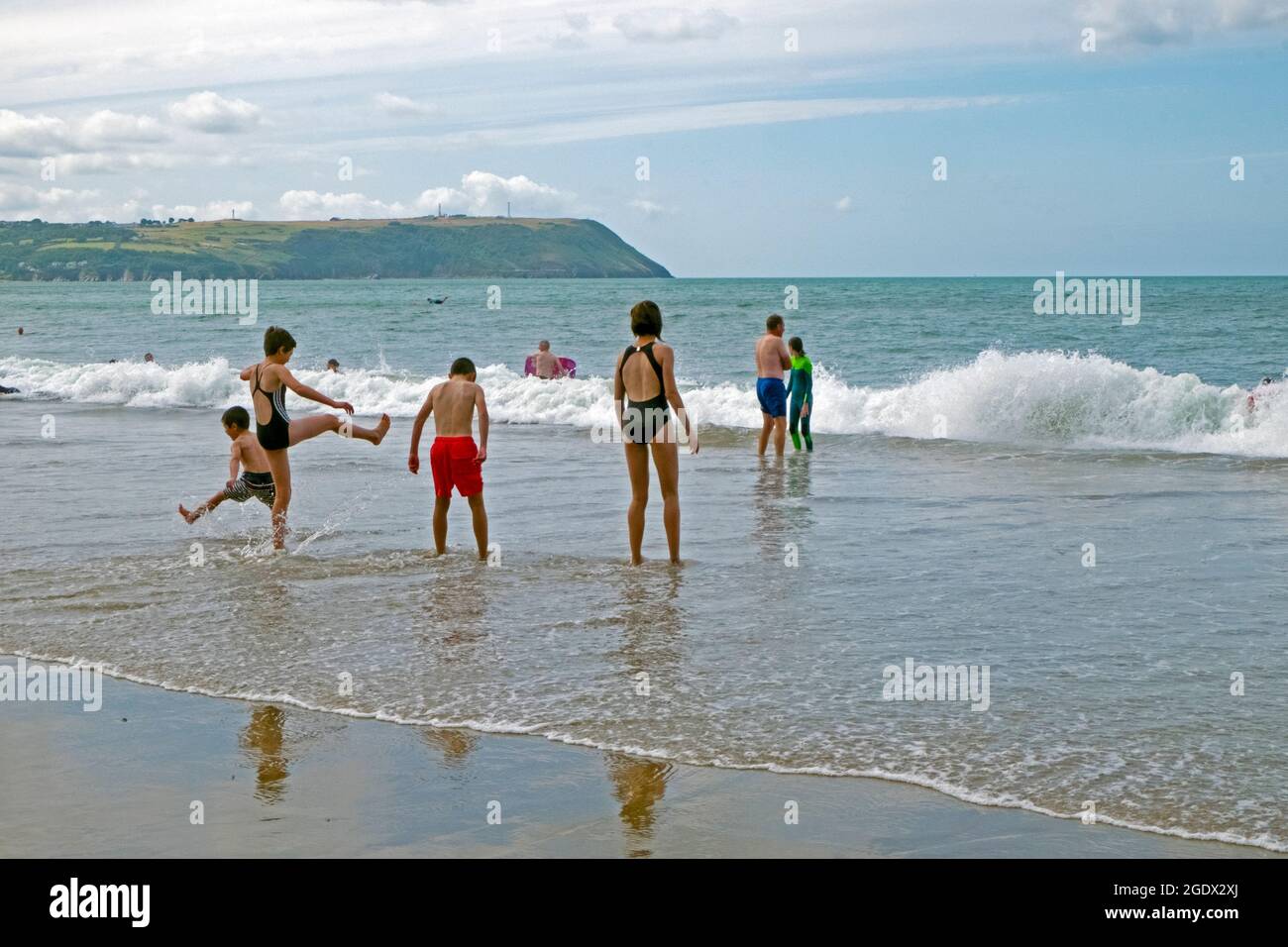 Children people holidaymakers on the Ceredigion Welsh Coast playing in the sea water chasing waves on the beach at Pen Bryn Wales UK 2021 KATHY DEWITT Stock Photo