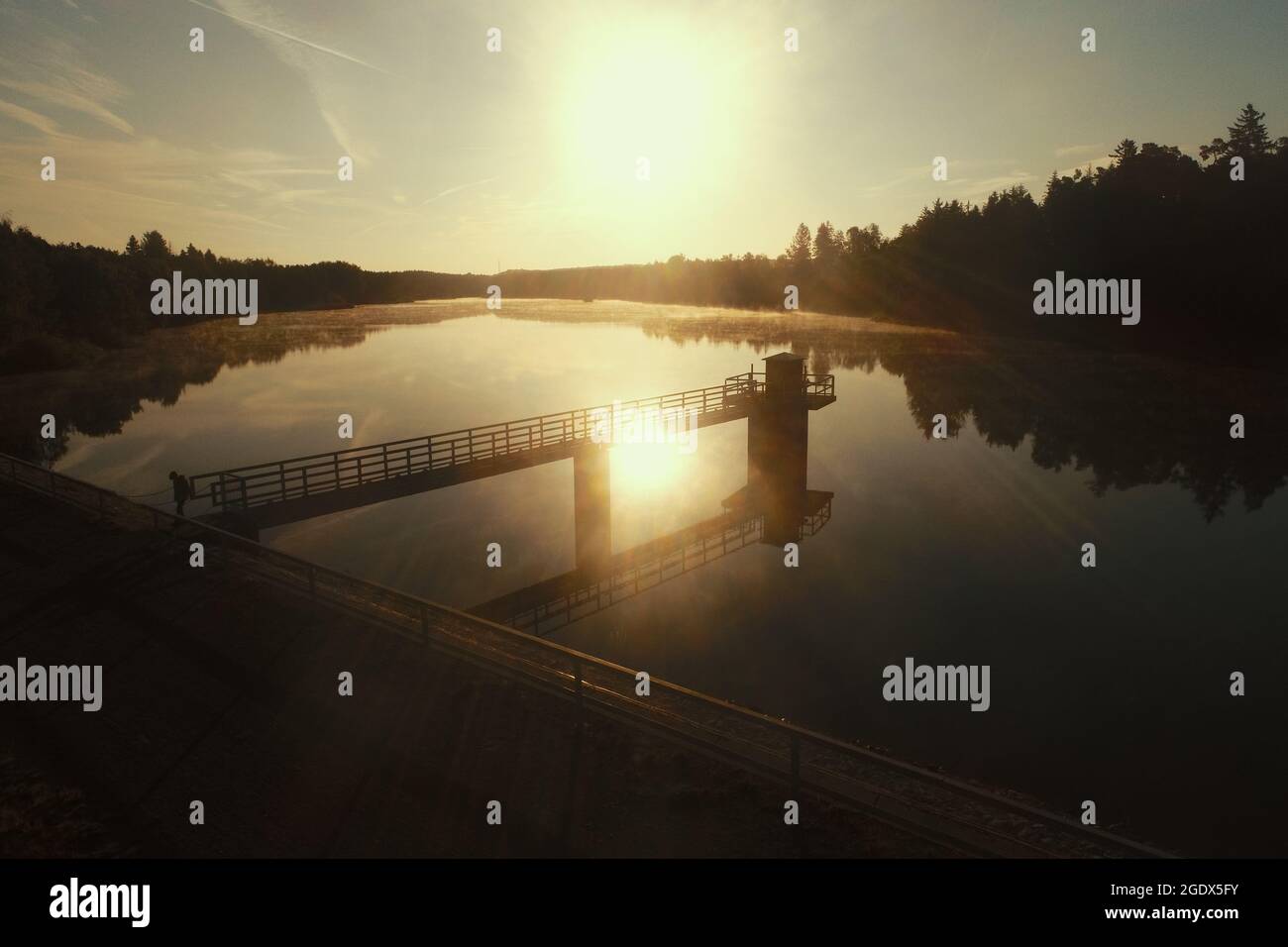 Harzgerode, Germany. 15th Aug, 2021. The light of the morning sun shines on the Teufelsteich near Harzgerode. The pond was created in the 17th century to ensure the supply of the surrounding mines with water power. The pond owes its name to the Teufelsberg near Silberhütte. Since 1945 the pond has been used as a drinking water reservoir. It can accumulate up to 785000 cubic metres of water. Because of its size, the reservoir has the status of a dam. Credit: Matthias Bein/dpa-Zentralbild/ZB/dpa/Alamy Live News Stock Photo