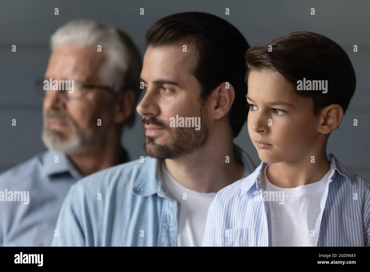 Three generations of men look in distance thinking Stock Photo