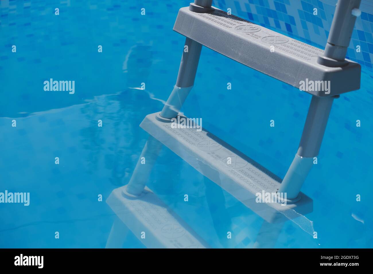 Ladder submerged in clear blue swimming pool water Stock Photo