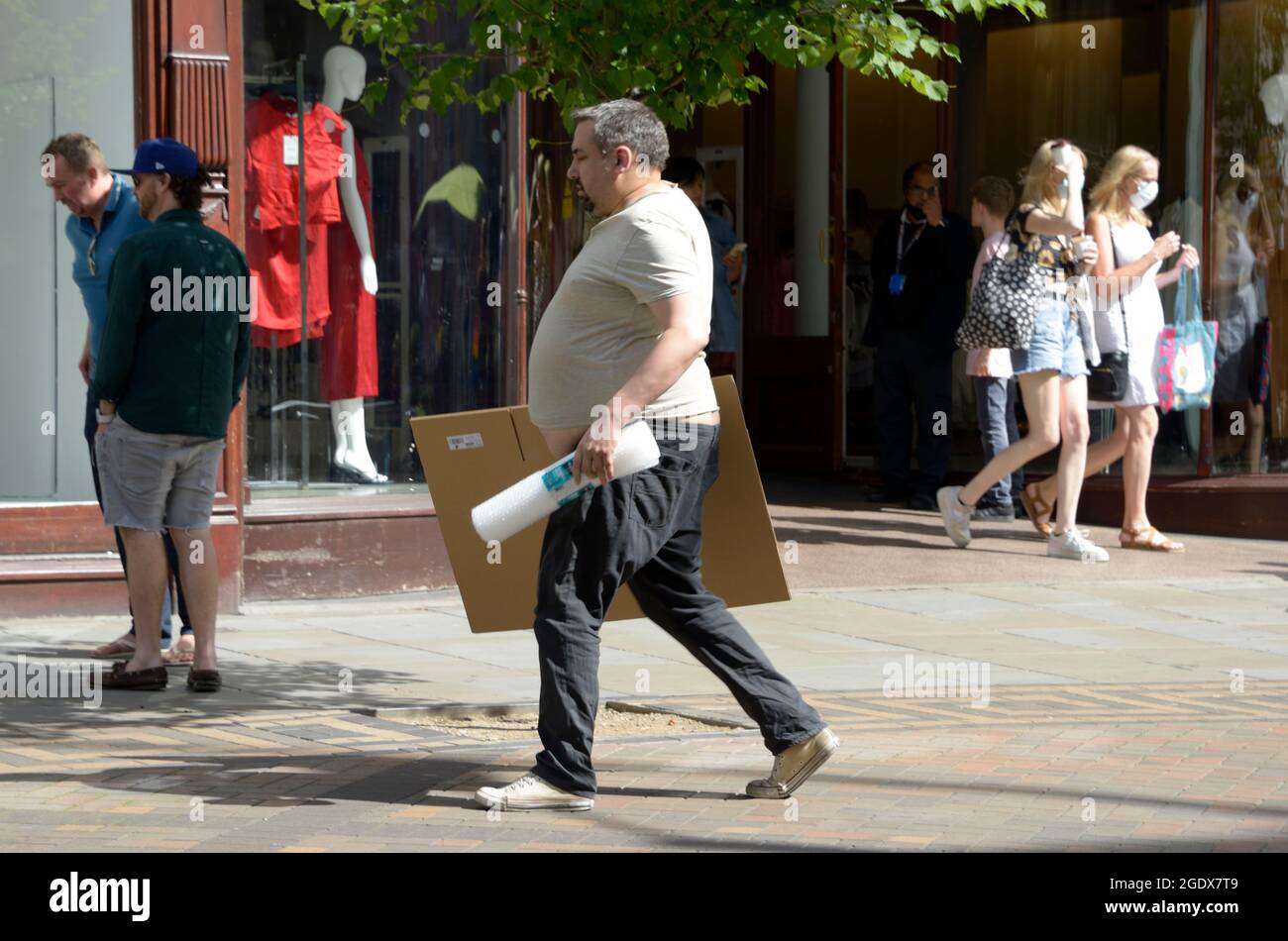 Obese man with shopping. Trousers slung low. Stock Photo