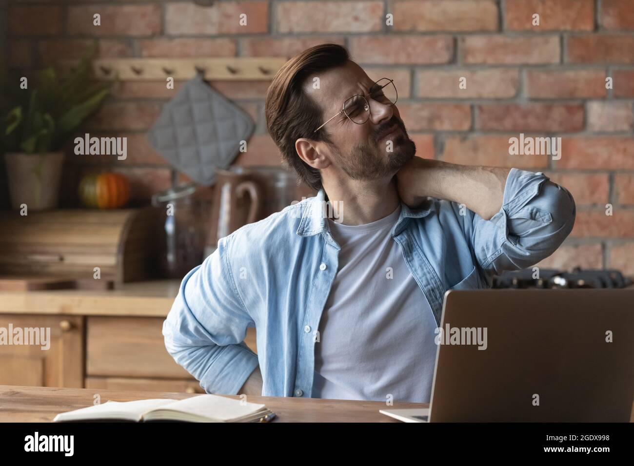 Unhealthy young man struggle with backache at workplace Stock Photo