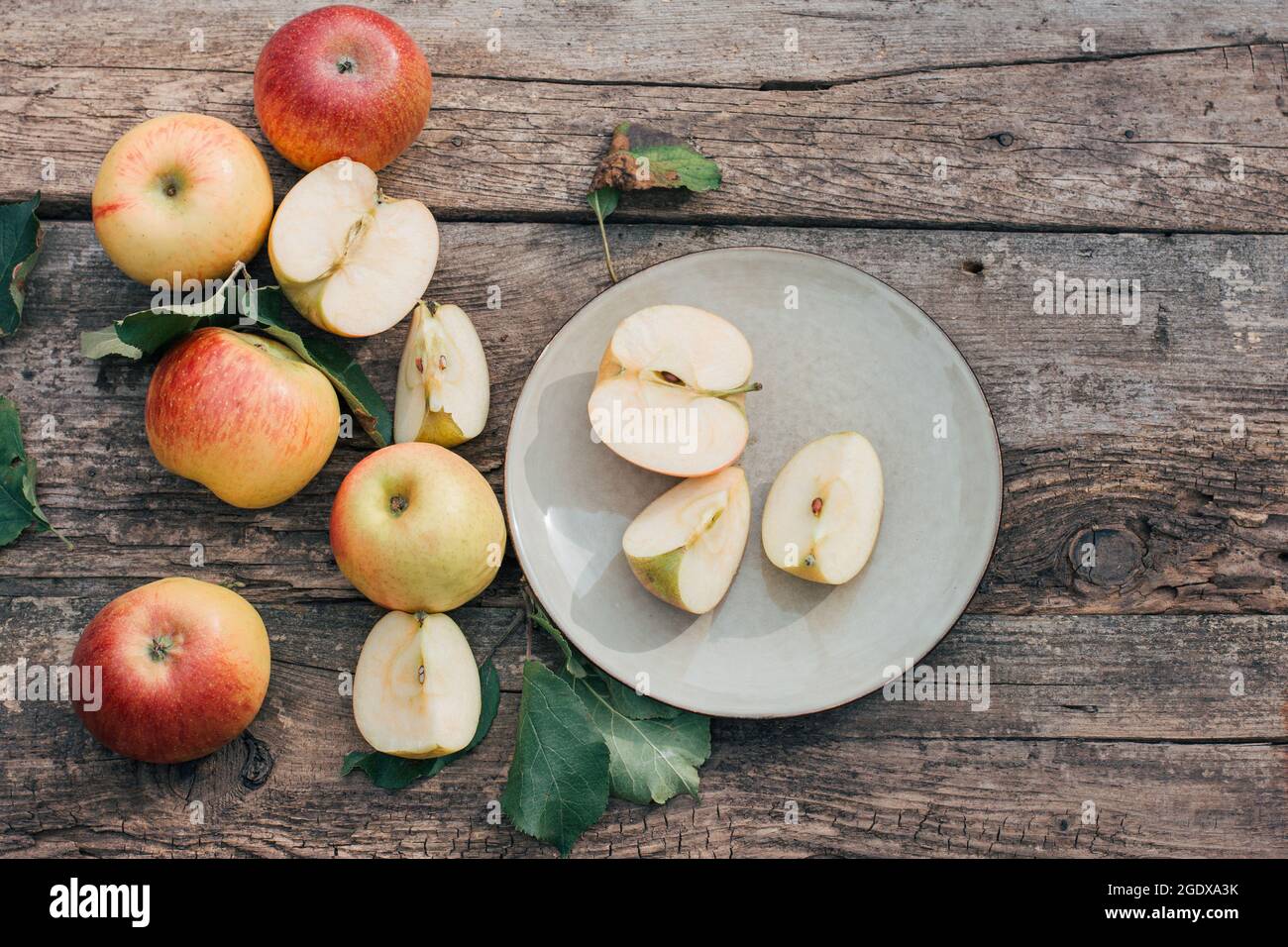 Red apples are lying on a plate and a wooden table. Harvest season, cooking at home, autumn food and holiday Stock Photo