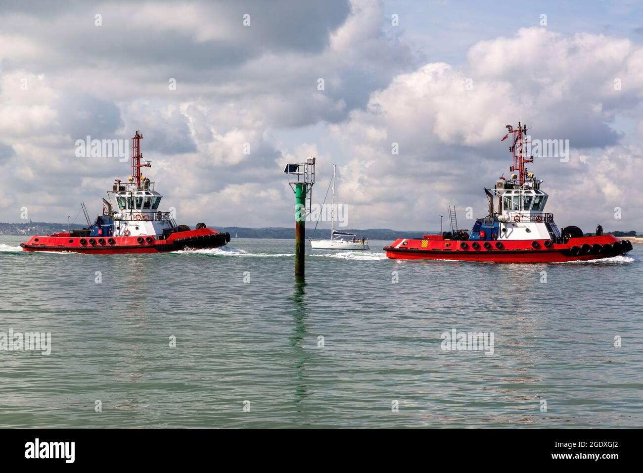 A pair of tug boats sailing into harbour Stock Photo