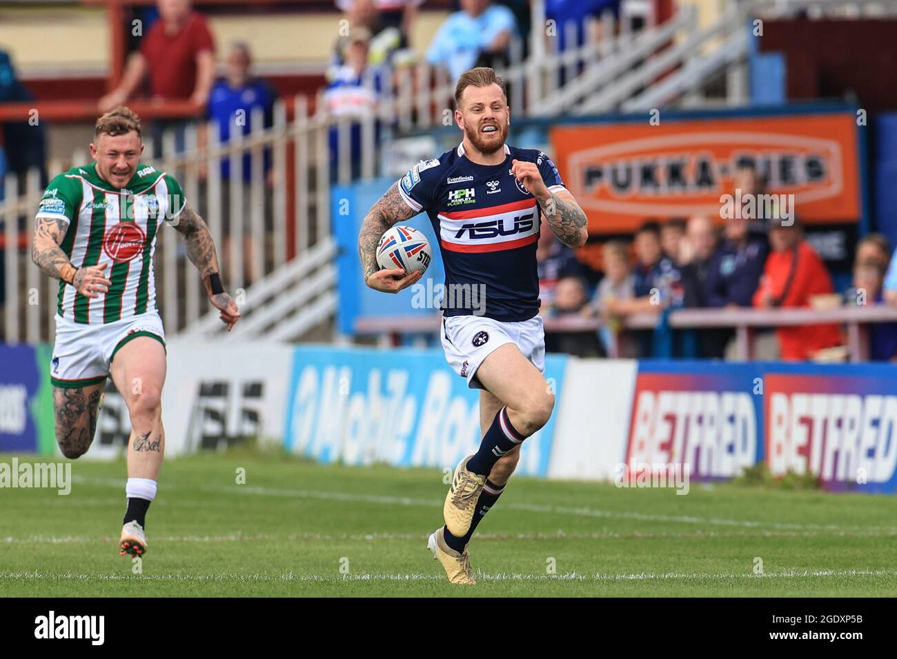 Tom Johnstone (2) of Wakefield Trinity makes a 70 yard dash to go over leaving Josh Charnley (5) of Warrington Wolves behind Stock Photo