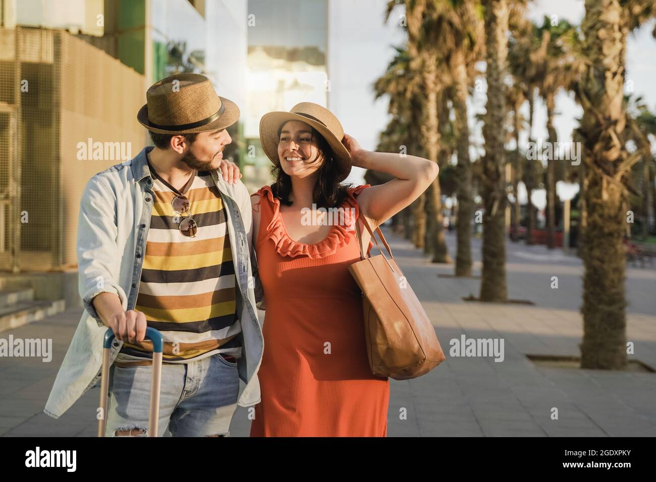 Young couple having fun outside airport with suitcase to celebrate their honeymoon - Focus on girl face Stock Photo