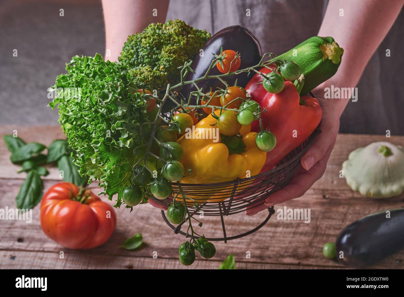 Female hand holding a basket with fresh vegetables and fruits on old ...