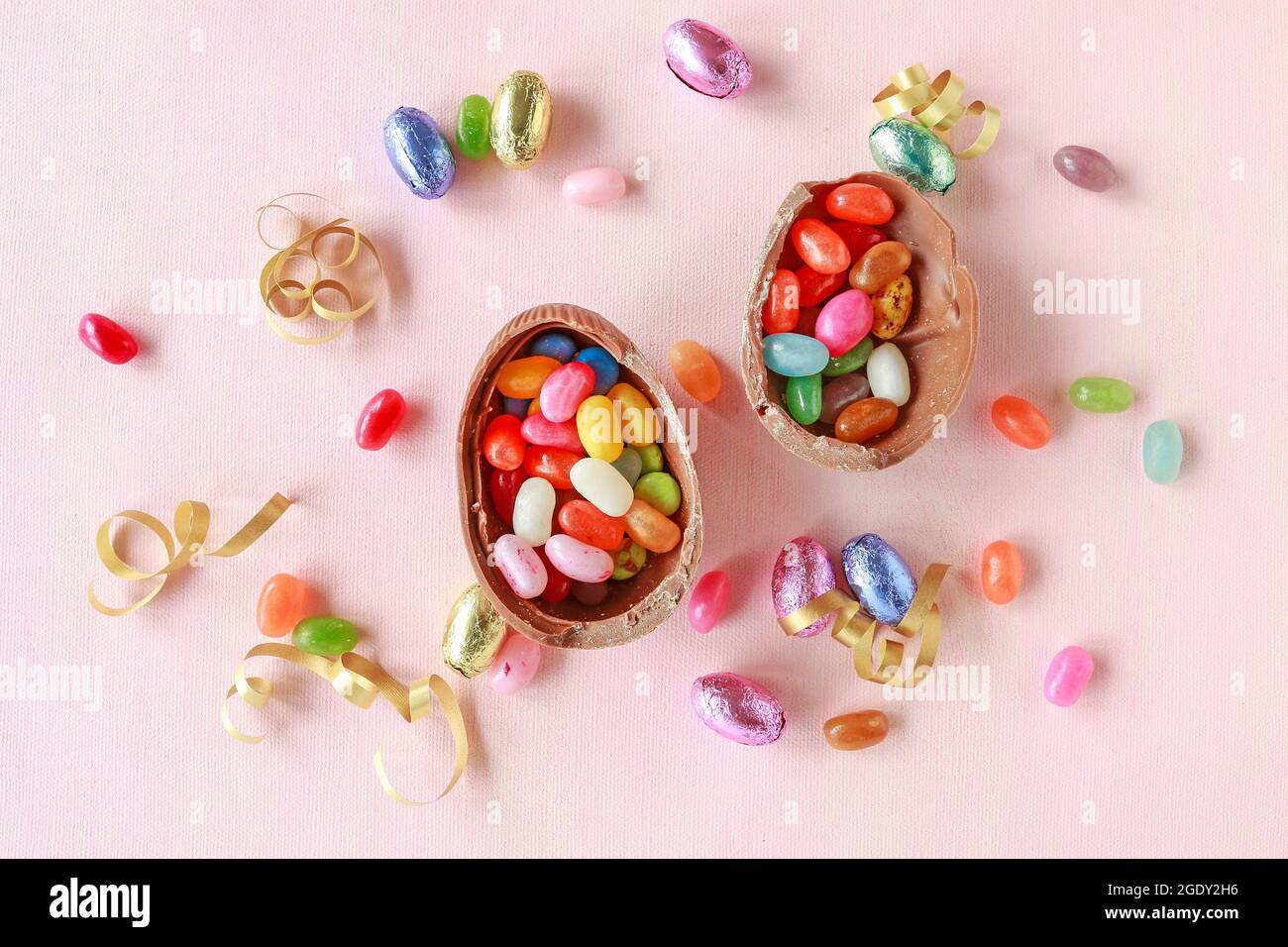 Chocolate Easter eggs and other sweets on pink background. Festive time Stock Photo
