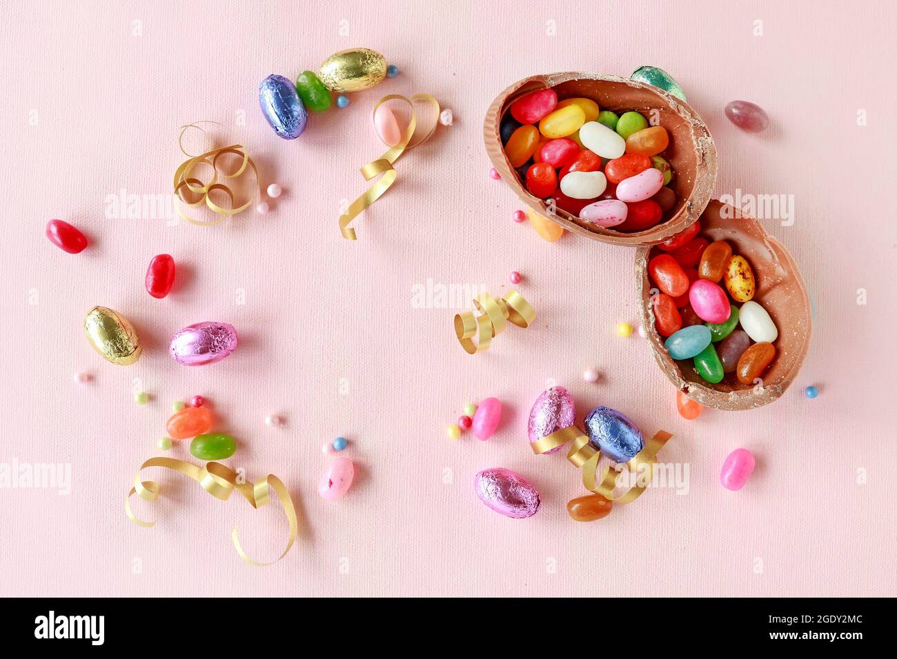 Chocolate Easter eggs and other sweets on pink background. Festive time Stock Photo