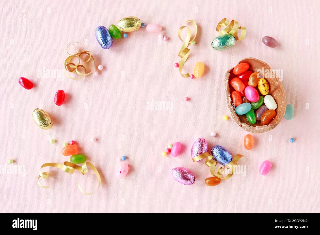 Chocolate Easter eggs and other sweets on pink background. Festive time Stock Photo
