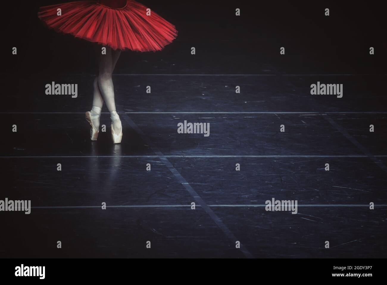 A ballerina wearing a red dress and performing on the dark stage Stock ...