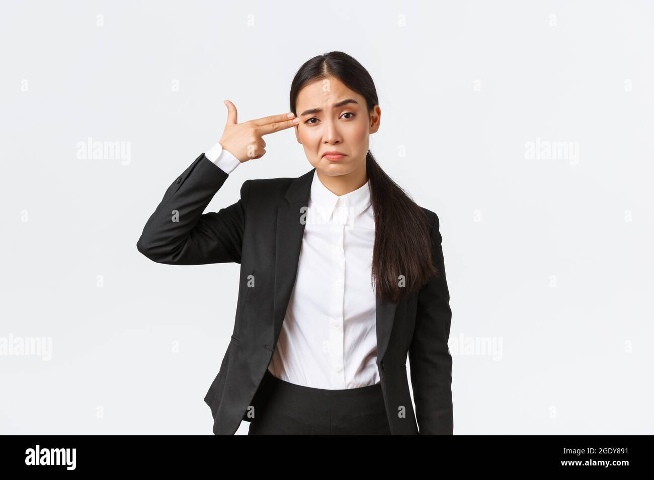 Just shoot me please. Bothered and fed up asian saleswoman hate her work,  standing in business suit, shooting herself with hand gun gesture as  feeling Stock Photo - Alamy