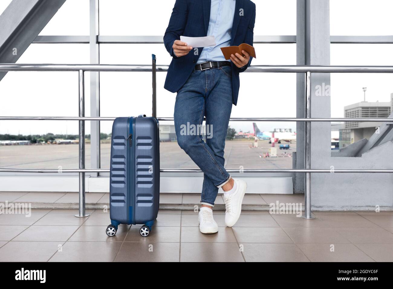Unrecognizable Man Checking Boarding Time In Tickets While Standing At Airport Terminal Stock Photo