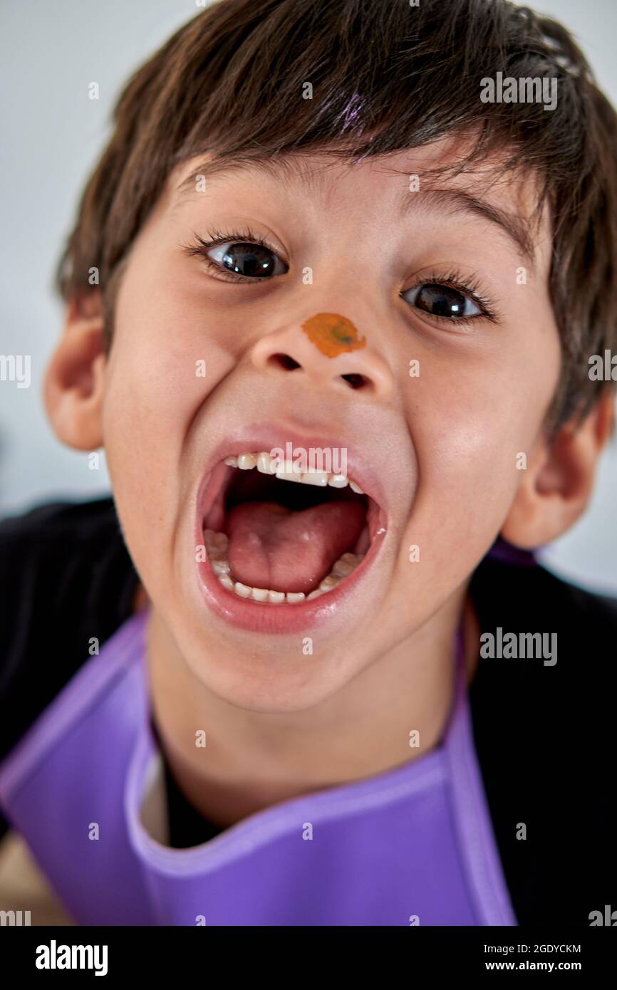 close up portrait of latin boy shouting happily with painted nose. vertical Stock Photo