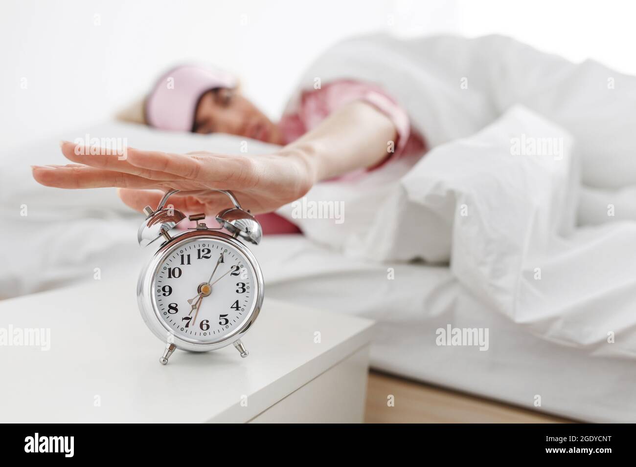 Alarm clock ringing, woman waking up in early morning for work, sleeping disorder Stock Photo