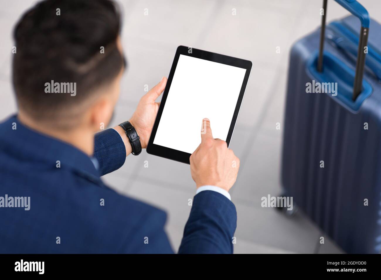 Man Using Digital Tablet With Blank Screen While Sitting With Luggage Outdoors Stock Photo