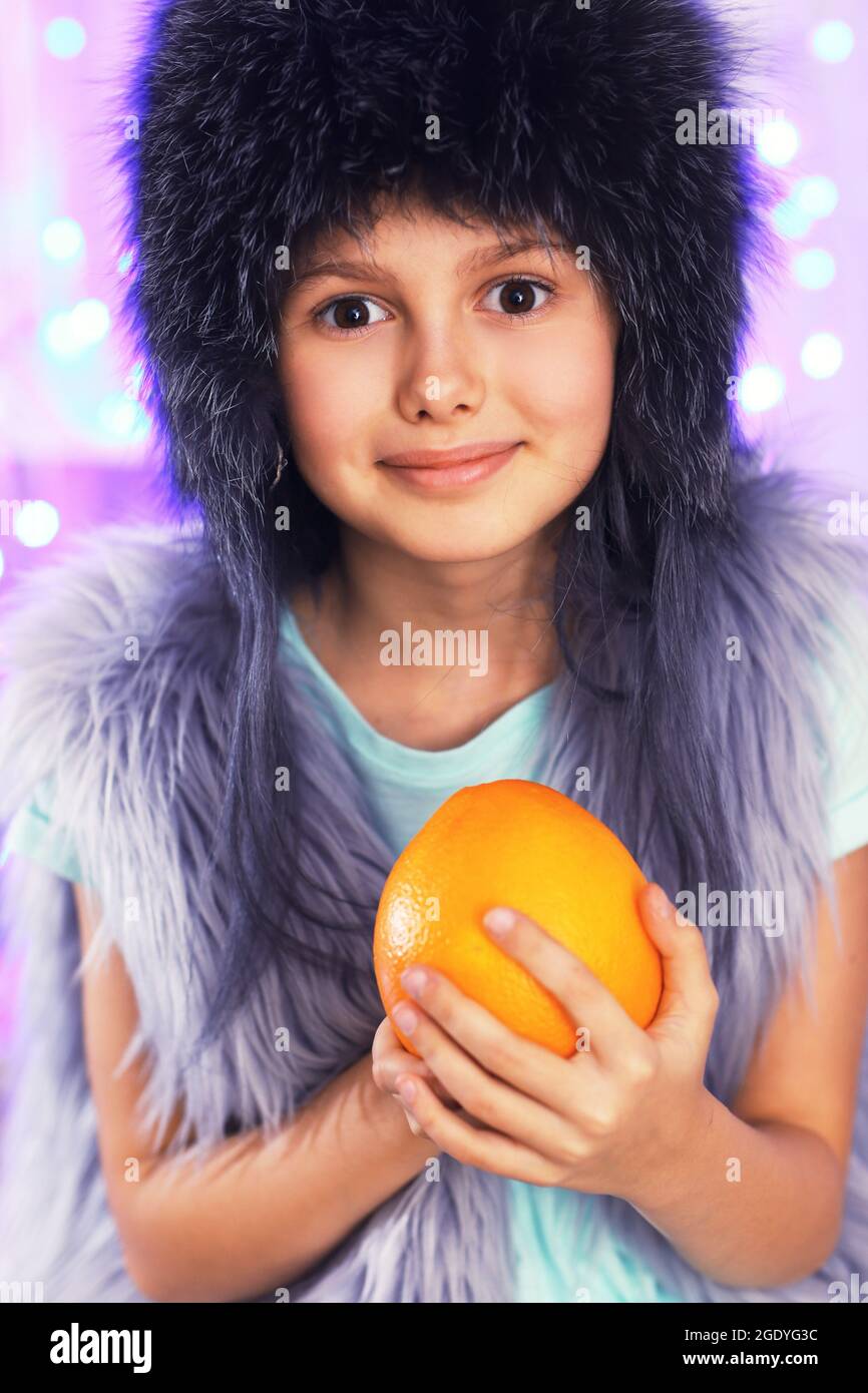 Cute little girl with orange on lights background Stock Photo Alamy