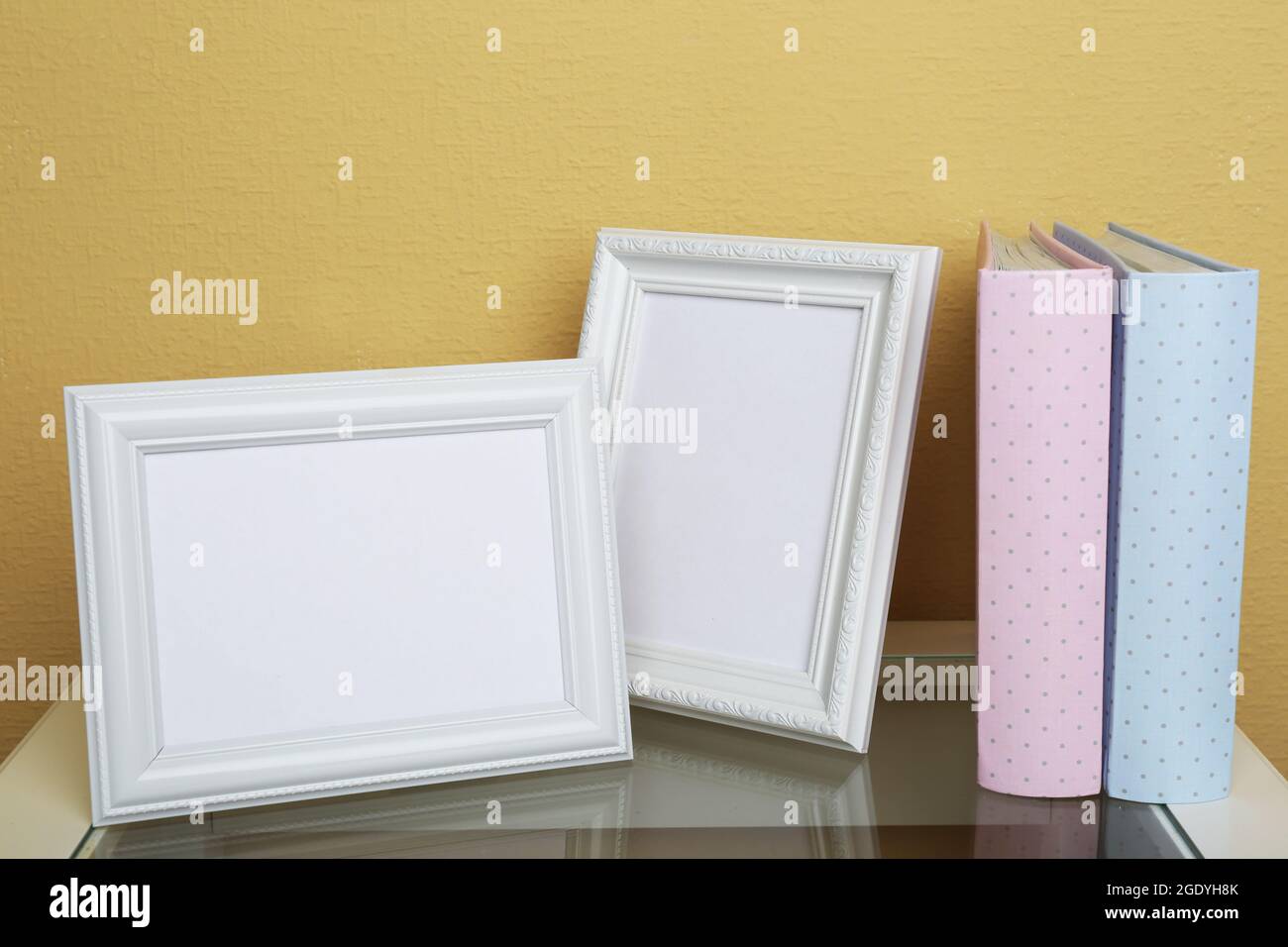 Photo frames with albums on coffee table on wallpaper background Stock