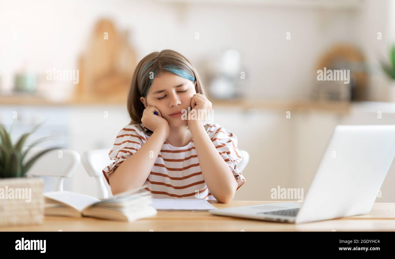 Back to school. Unhappy child is sitting at desk. Girl doing homework or online education. Stock Photo
