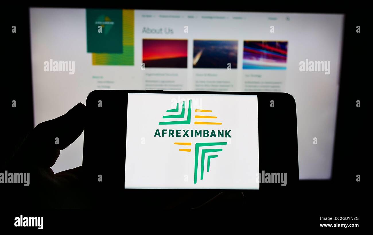 Person holding smartphone with logo of company African Export–Import Bank (Afreximbank) on screen in front of website. Focus on phone display. Stock Photo