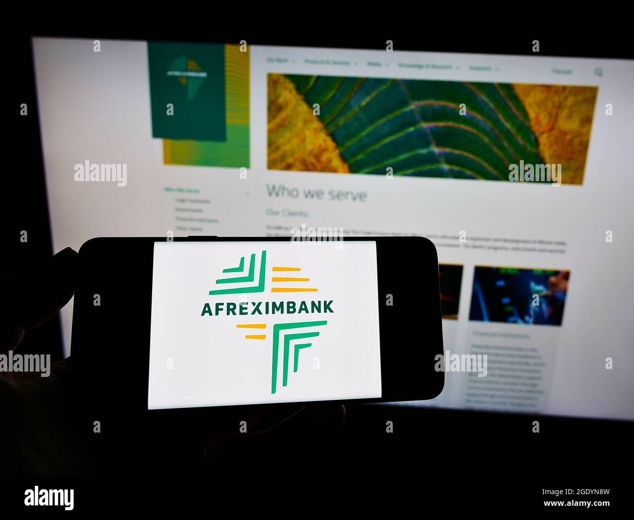 Person holding cellphone with logo of company African Export–Import Bank (Afreximbank) on screen in front of webpage. Focus on phone display. Stock Photo