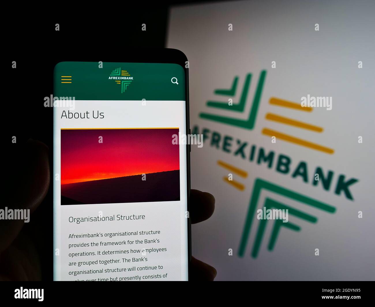 Person holding smartphone with website of company African Export–Import Bank (Afreximbank) on screen with logo. Focus on center of phone display. Stock Photo