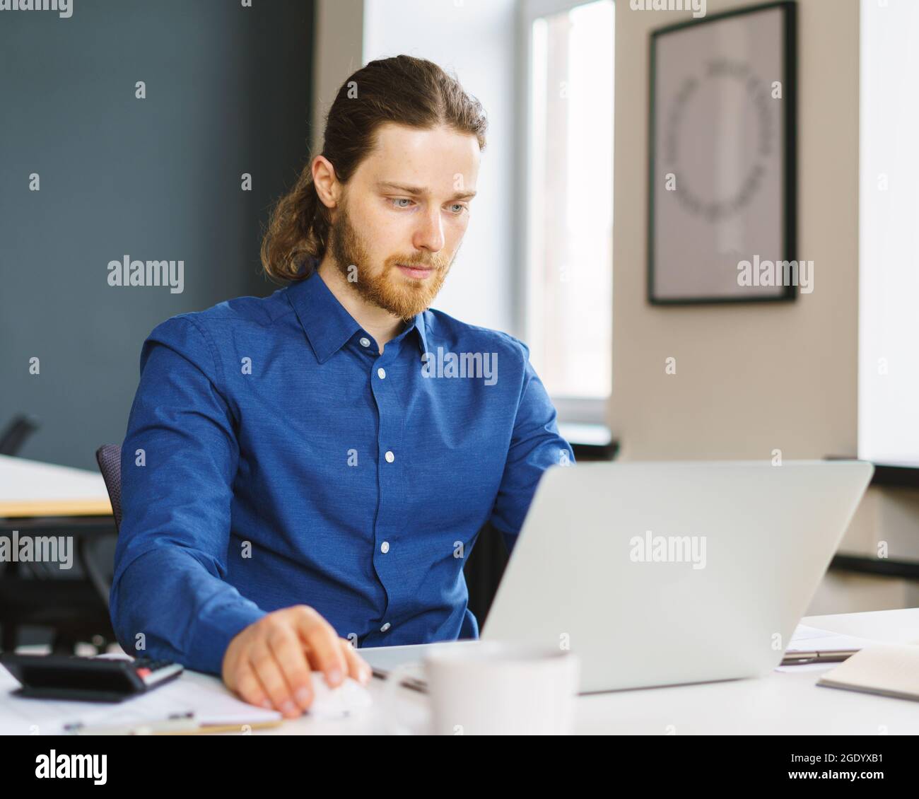 Young focused man freelancer working on laptop computer remotely Stock Photo