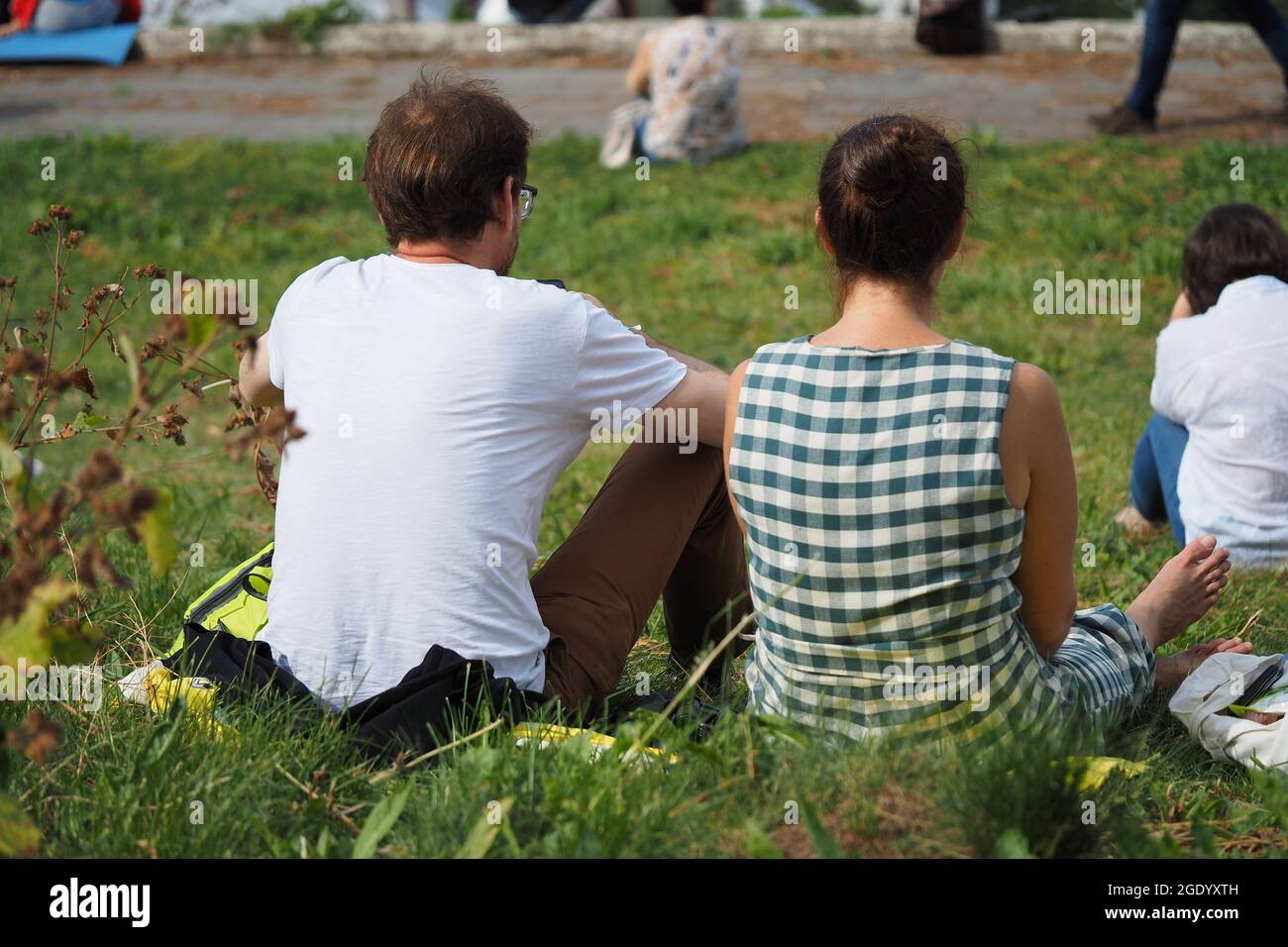 People relax in the park outdoors, sit in the summer on the lawn. Stock Photo