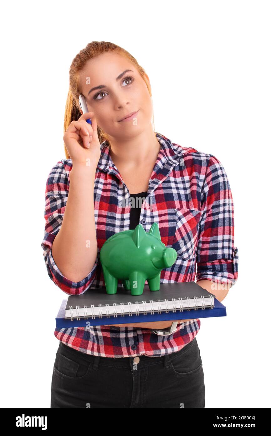 Young female student holding a green piggy bank on a stack of books ...