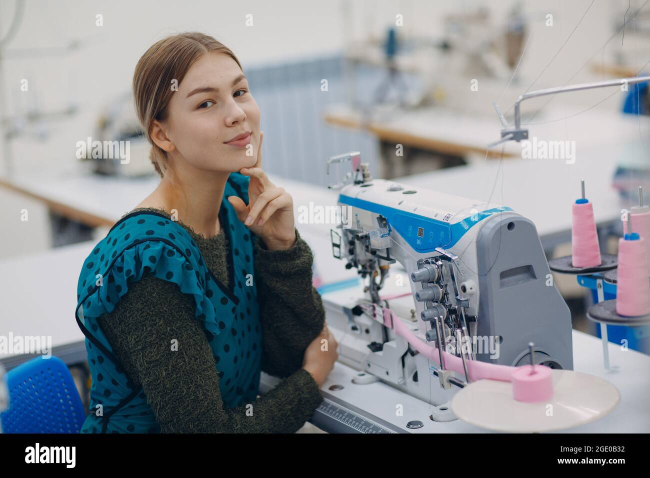 Young beautiful seamstress sews on sewing machine in factory Stock ...