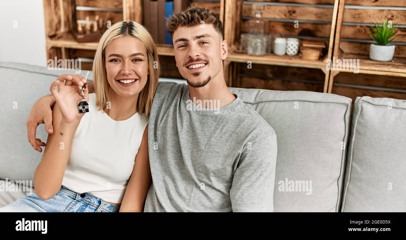 Young caucasian couple smiling happy holding key of new home sititng on ...