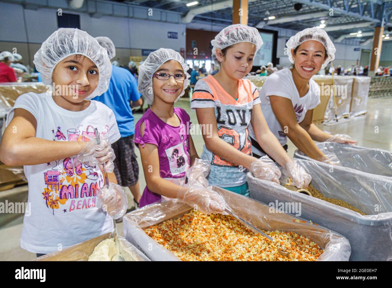 Miami Florida,Feed My Starving Children,volunteers volunteering,working together preparing packing meals,Hispanic girls students wearing hairnets Stock Photo