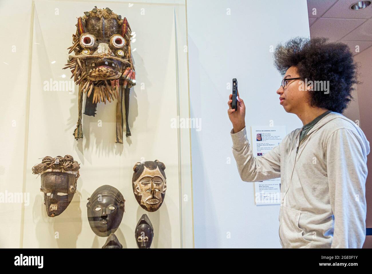 Orlando Florida,Museum of Art OMA,African art artwork exhibit exhibition collection ceremonial face masks,Black teen teenager smartphone camera takes Stock Photo