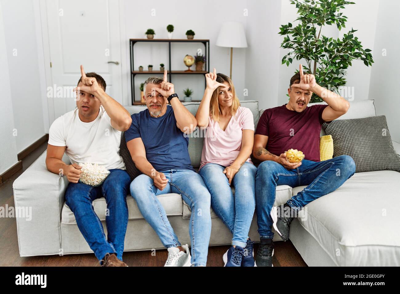 vlot Beoefend Verbieden Group of middle age people sitting on the sofa at home making fun of people  with fingers on forehead doing loser gesture mocking and insulting Stock  Photo - Alamy