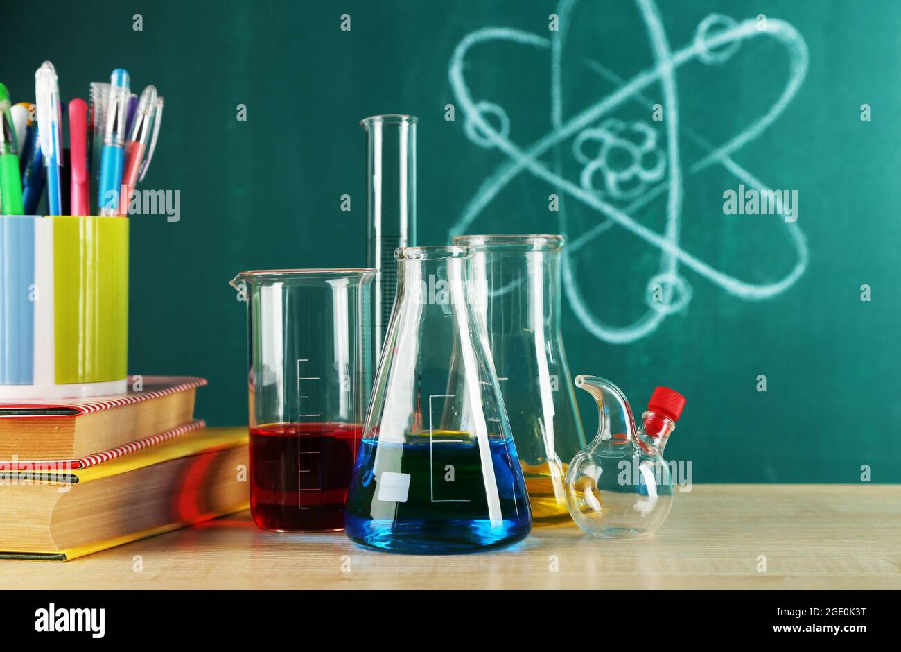Desk in chemistry class with test tubes on green blackboard background