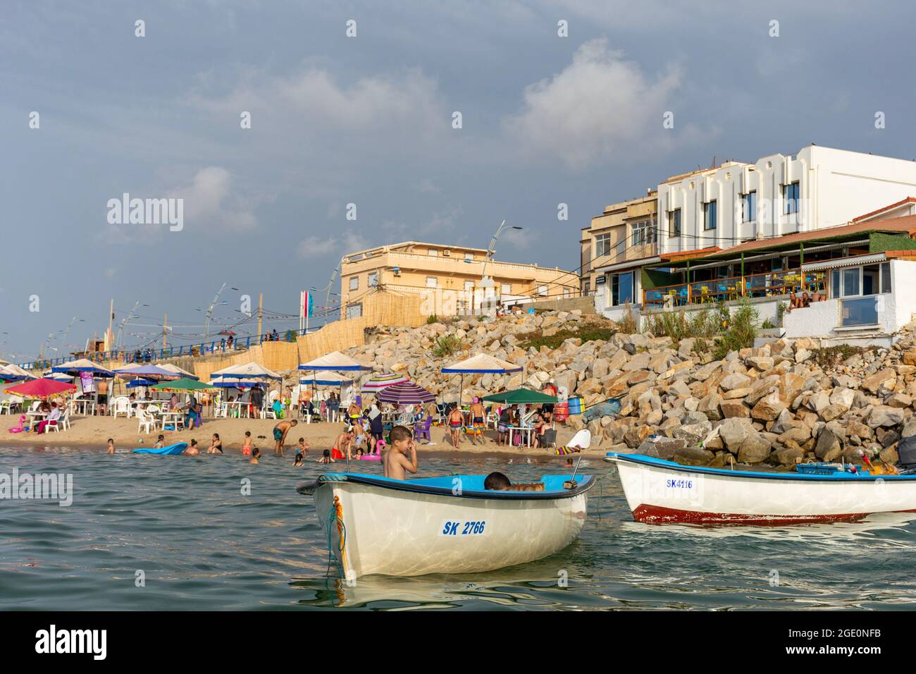 Low angle view of two boats and families having fun on the beach, kids playing in the water, Skikda, Algeria. Stock Photo